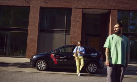 Miles Carsharing Car Yu Woman Leaning On Car Men In Foreground Kopie